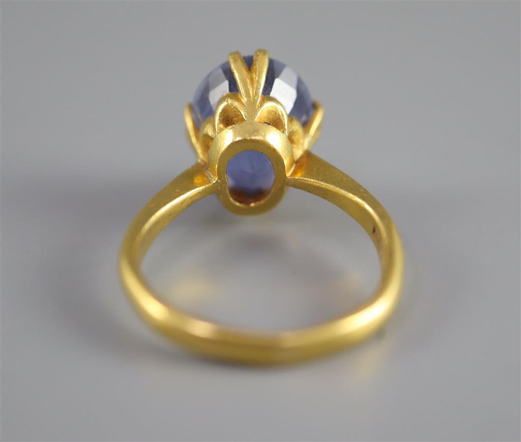 A gold (stamped 24k) and solitaire oval cut Ceylon sapphire set ring,